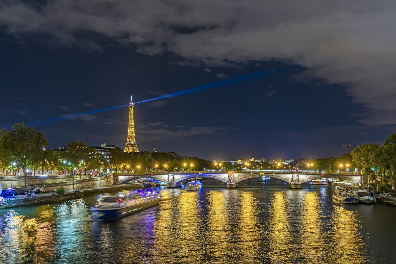 River cruise boats on the Seine at night with the Eiffel Tower lit up